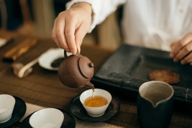 Người phụ nữ đang uống trà, ly trà ấm bốc khói.