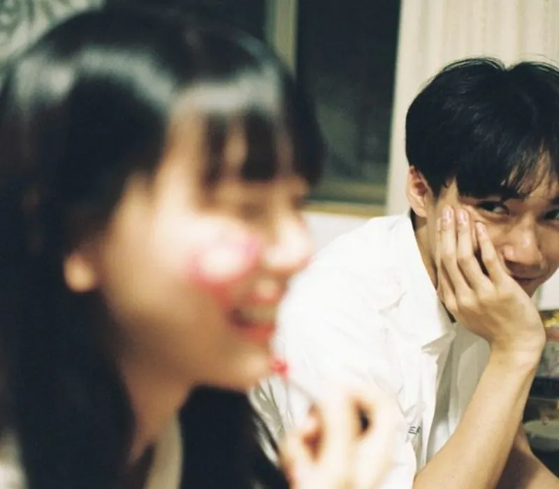 Hình ảnh một cặp đôi ngồi cạnh nhau, nắm tay, ánh mắt trìu mến