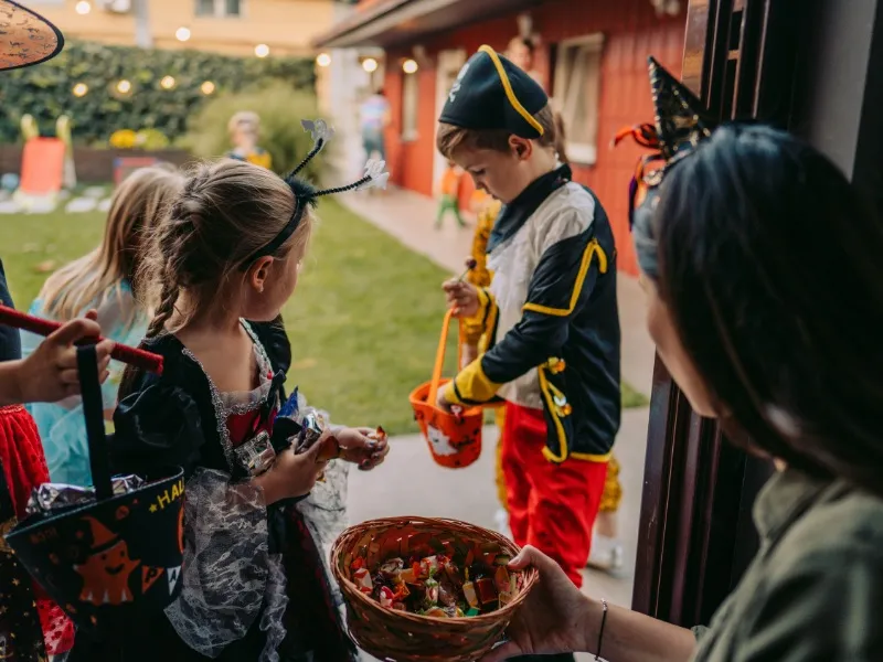 Gia đình và trẻ em cùng nhau vui chơi và chuẩn bị cho hoạt động Trick or Treat trong không khí lễ hội Halloween, thể hiện tinh thần cộng đồng.