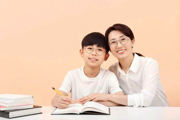 Một em bé đang học bài tại bàn, tập trung vào sách vở.