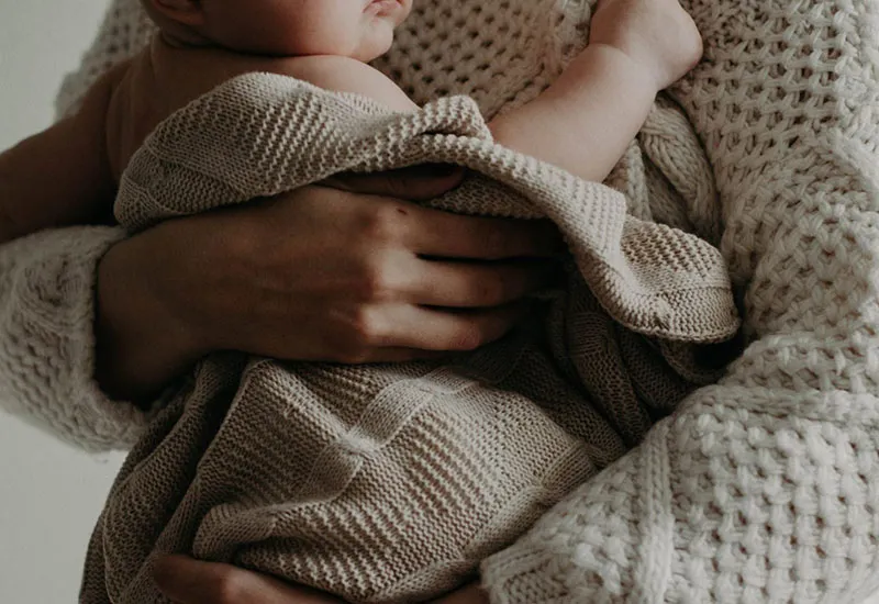 Hình ảnh trẻ sơ sinh bám mẹ, minh họa khái niệm bện hơi ban đầu và nhu cầu gắn kết