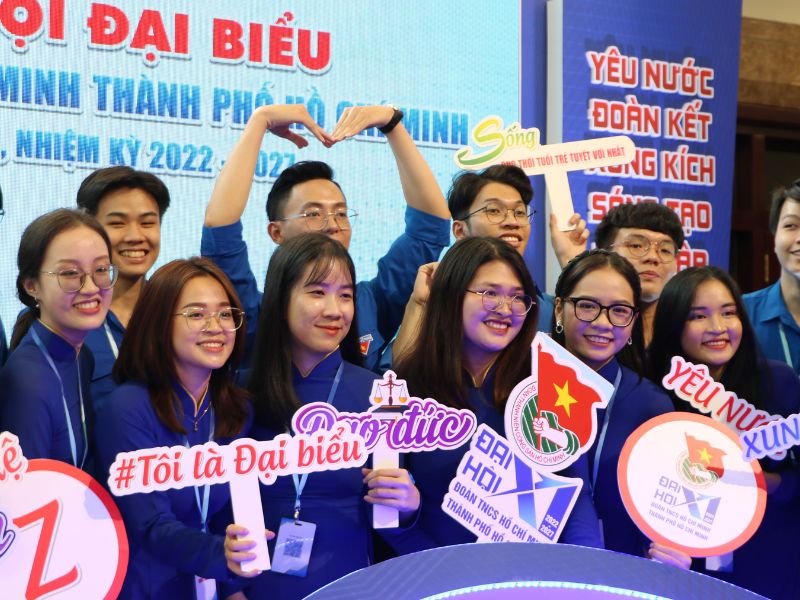 Hình ảnh tập thể đoàn viên Thanh niên Cộng sản Hồ Chí Minh đang giơ tay chào cờ, thể hiện tinh thần cống hiến và trưởng thành
