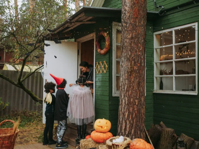 Trẻ em hóa trang thành phù thủy và bí ngô, chơi Trick or Treat vui vẻ trong đêm Halloween, biểu tượng của sự hào phóng và nghịch ngợm.