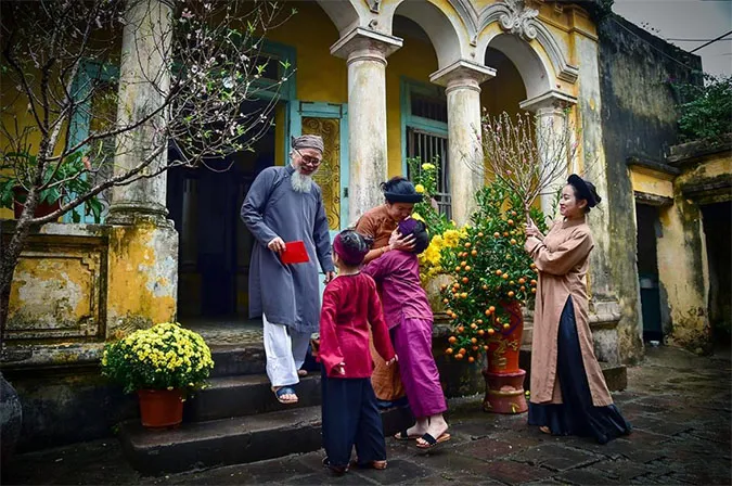 Người phụ nữ vui vẻ xông đất mang theo may mắn cho gia chủ vào sáng mùng một Tết Nguyên Đán, tượng trưng cho khởi đầu năm mới tốt lành.