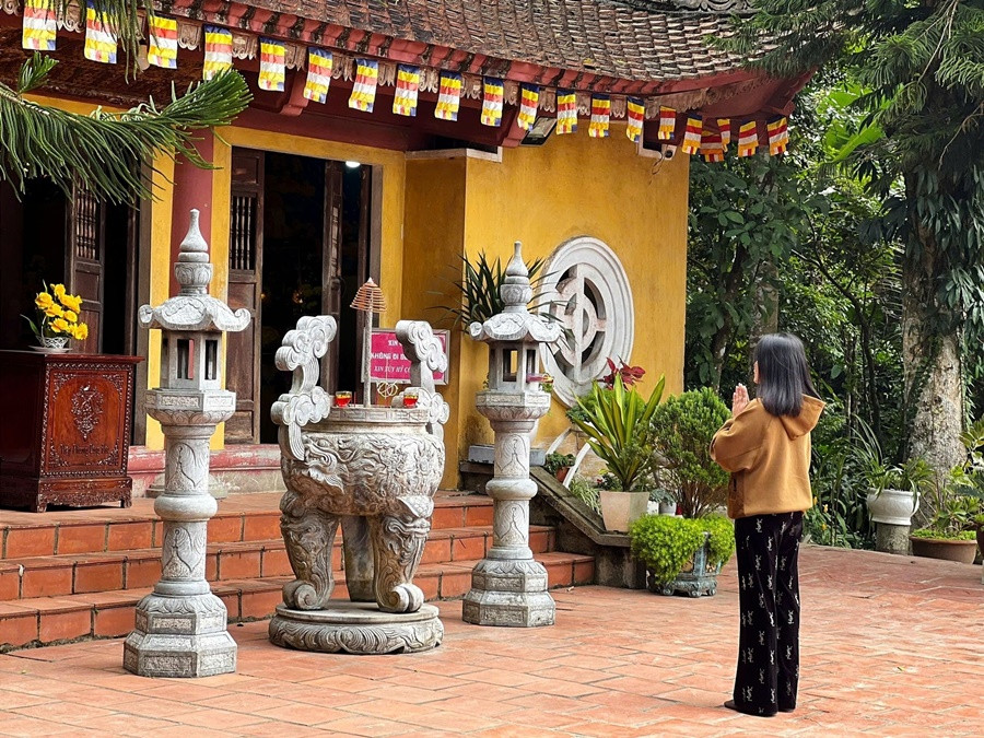 Một Phật tử thực hiện nghi thức cầu khấn trước lư hương đá, bày tỏ ước nguyện khi đến lễ Đền Tây Thiên.