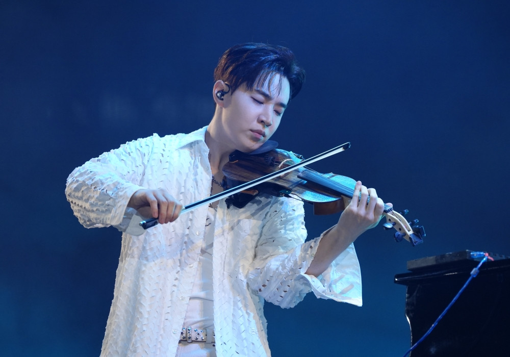 Henry Lau trên sân khấu biểu diễn với cây đàn violin, thể hiện tài năng âm nhạc đa dạng
